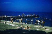 Swimmers on beach and long concrete pier